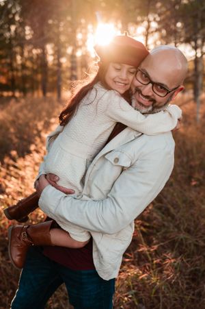 Warm sunset portrait of parent and child hugging in matching white sweaters.
