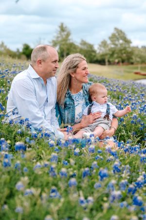 Family lying together in a field of blooming bluebonnets on a spring day.