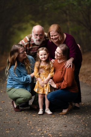 A family group shares joyful moments together during an autumn outdoor photo session.