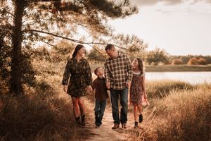 Silhouetted family walking together through a golden field at sunset.