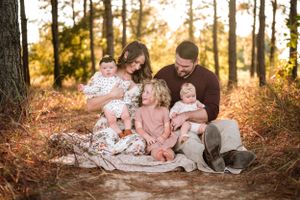 Family portrait session in a rustic outdoor setting with warm autumn colors.