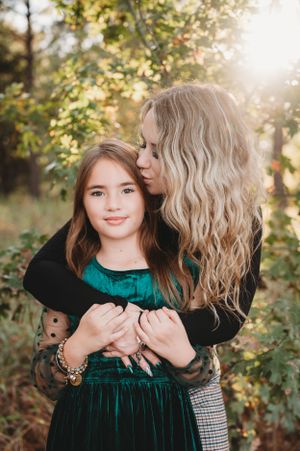 Sweet portrait session featuring emerald velvet dress against autumn foliage backdrop.