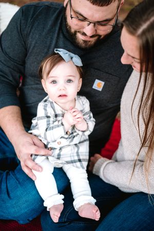 Cozy family portrait session with neutral tones and plaid baby outfit.