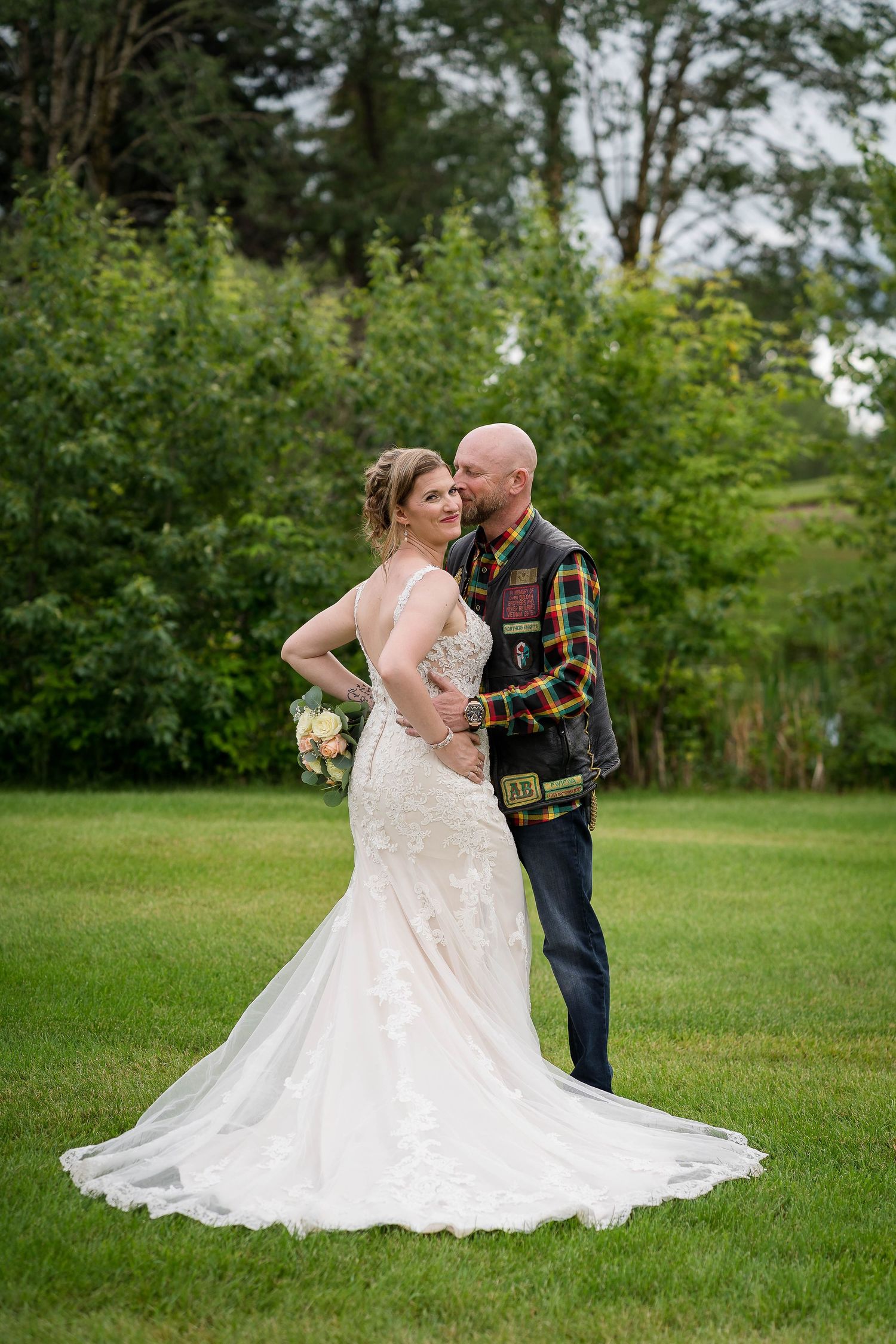 Wedding ceremony taking place under an elegant floral arch decorated with peach roses and greenery.