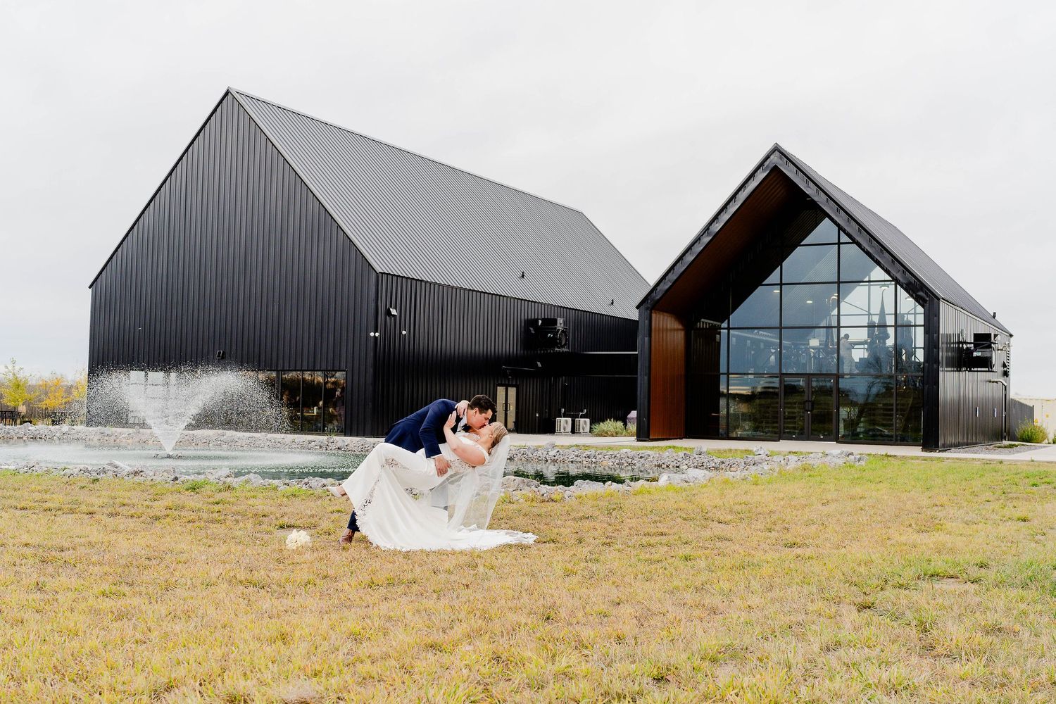 A wedding ceremony takes place on a cliffside overlooking a serene lake, surrounded by evergreen trees.