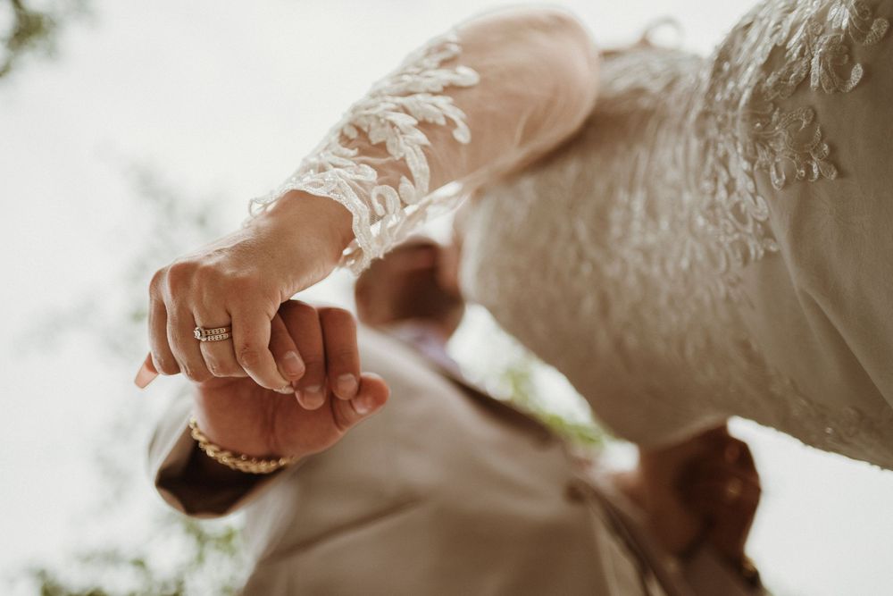 Close-up detail of delicate lace sleeve and wedding ring during a romantic bridal moment.