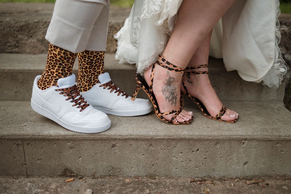 A row of wedding party feet showing various footwear styles including sneakers, heels, and leopard print shoes.