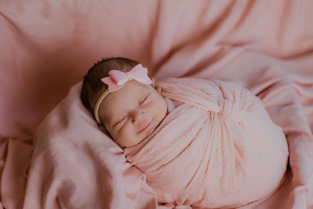 Peaceful newborn baby resting in soft pink surroundings.