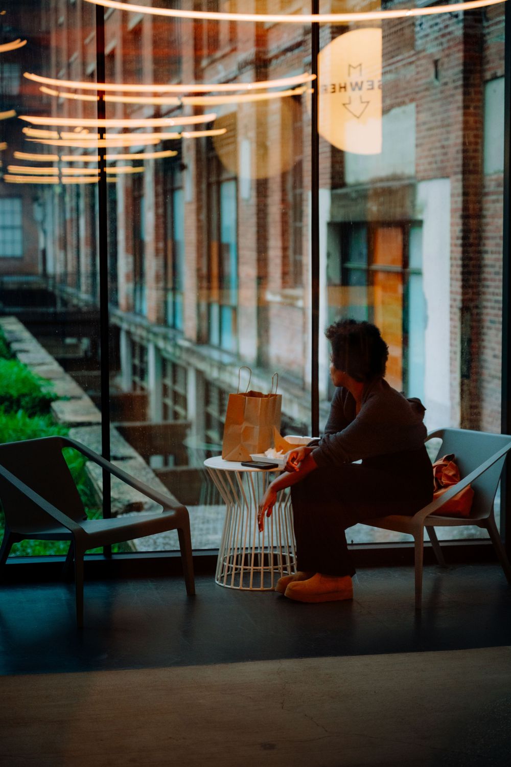 Modern office lounge area with string lights and brick walls in evening atmosphere.