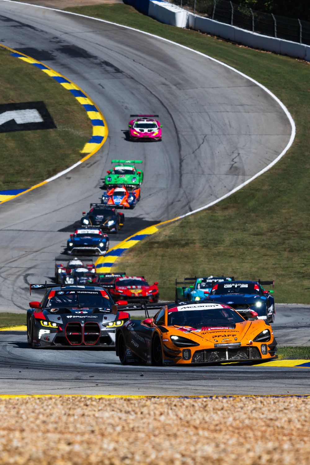 Colorful race cars navigate a curved section of track during a motorsport competition.