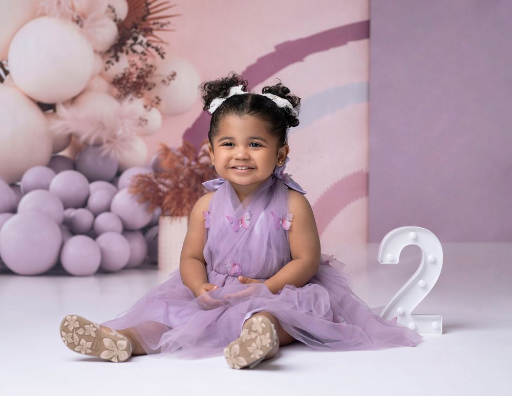 Miami Maternity photographer Professional birthday portrait with purple tulle dress against pastel balloon backdrop and number 2 decoration.