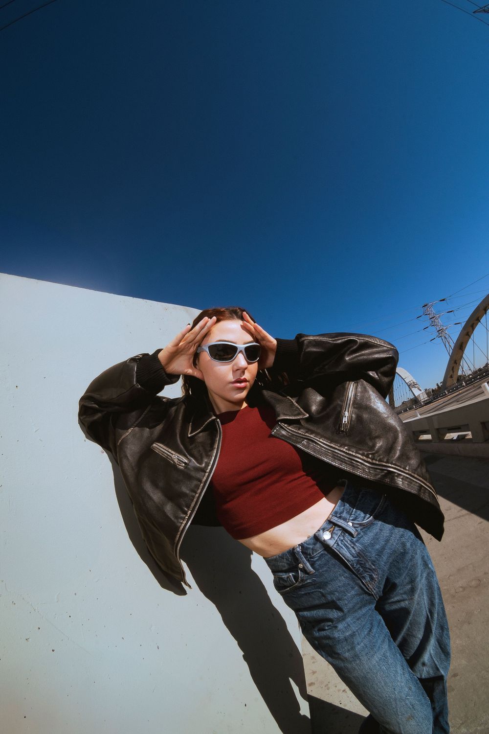 A model poses on the side of a bridge. Captured with a wide angle lens this vibrant image depicts a high fashion editorial scene