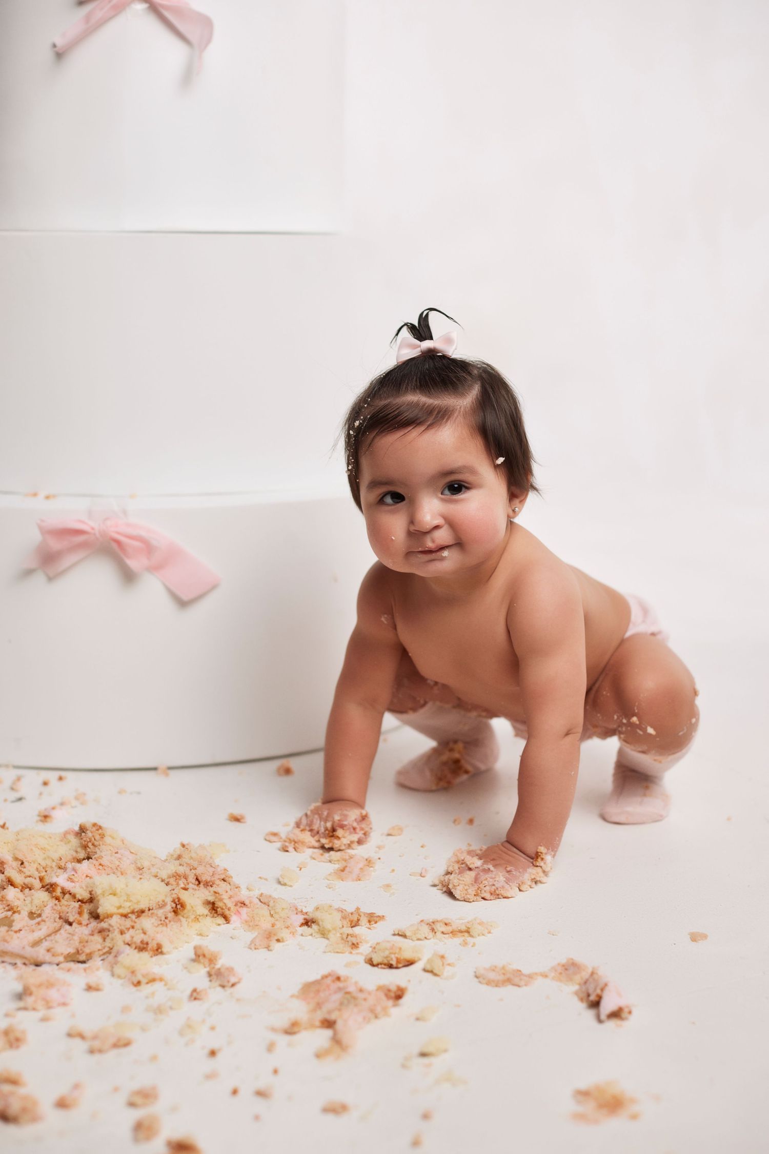 Cake smash photography session with baby crawling through scattered cake crumbs.