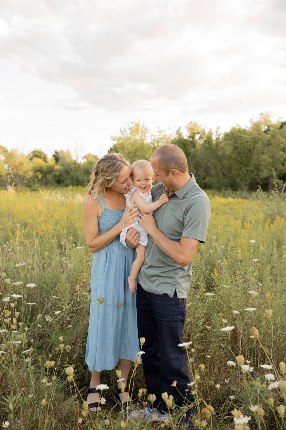 Family with toddler standing together in a wildflower meadow at sunset at bear creek nature preserve in Rochester Hills michigan