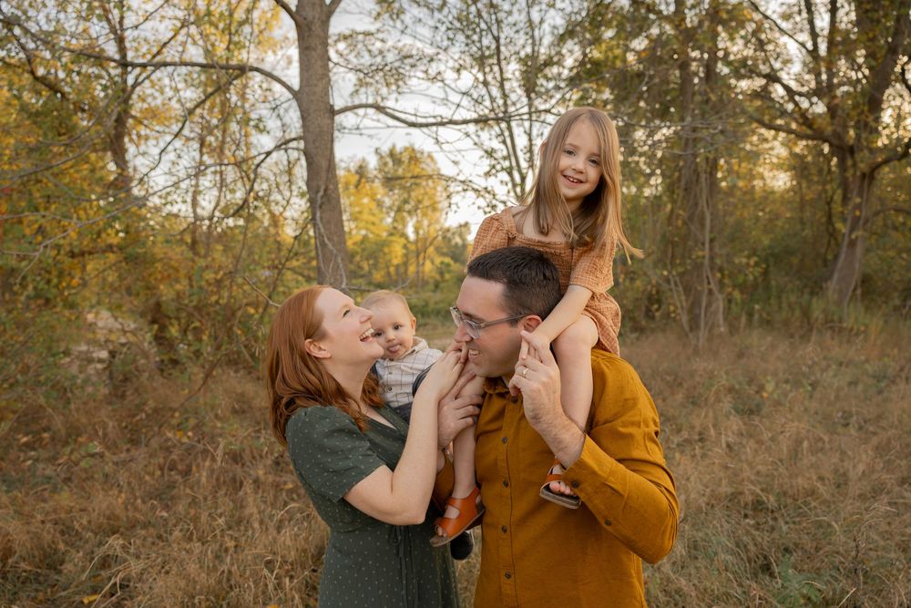 A family in fall outfits share tender moments during an autumn outdoor photoshoot in a wooded setting in Rochester Hills Romeo michigan