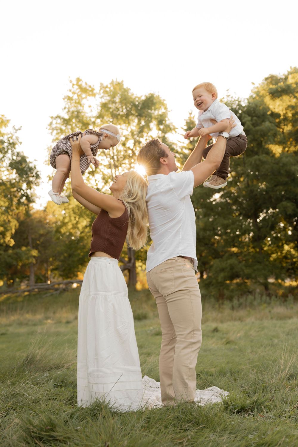 A couple throwing their toddlers into the air for a photoshoot in Lake Orion michigan