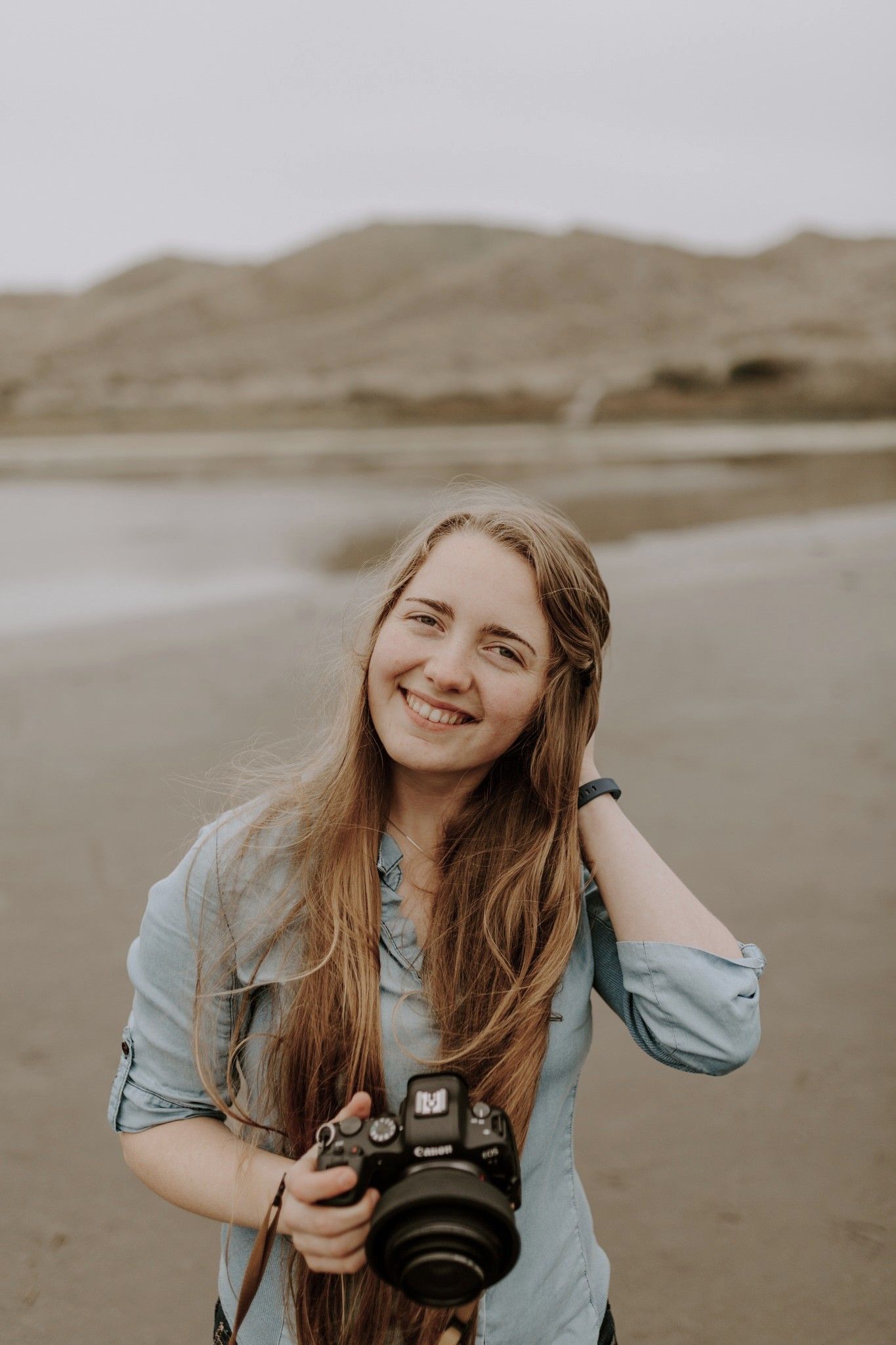 Portrait of photographer Taylor of Taylor Carpenter Photography holding her camera on the beach