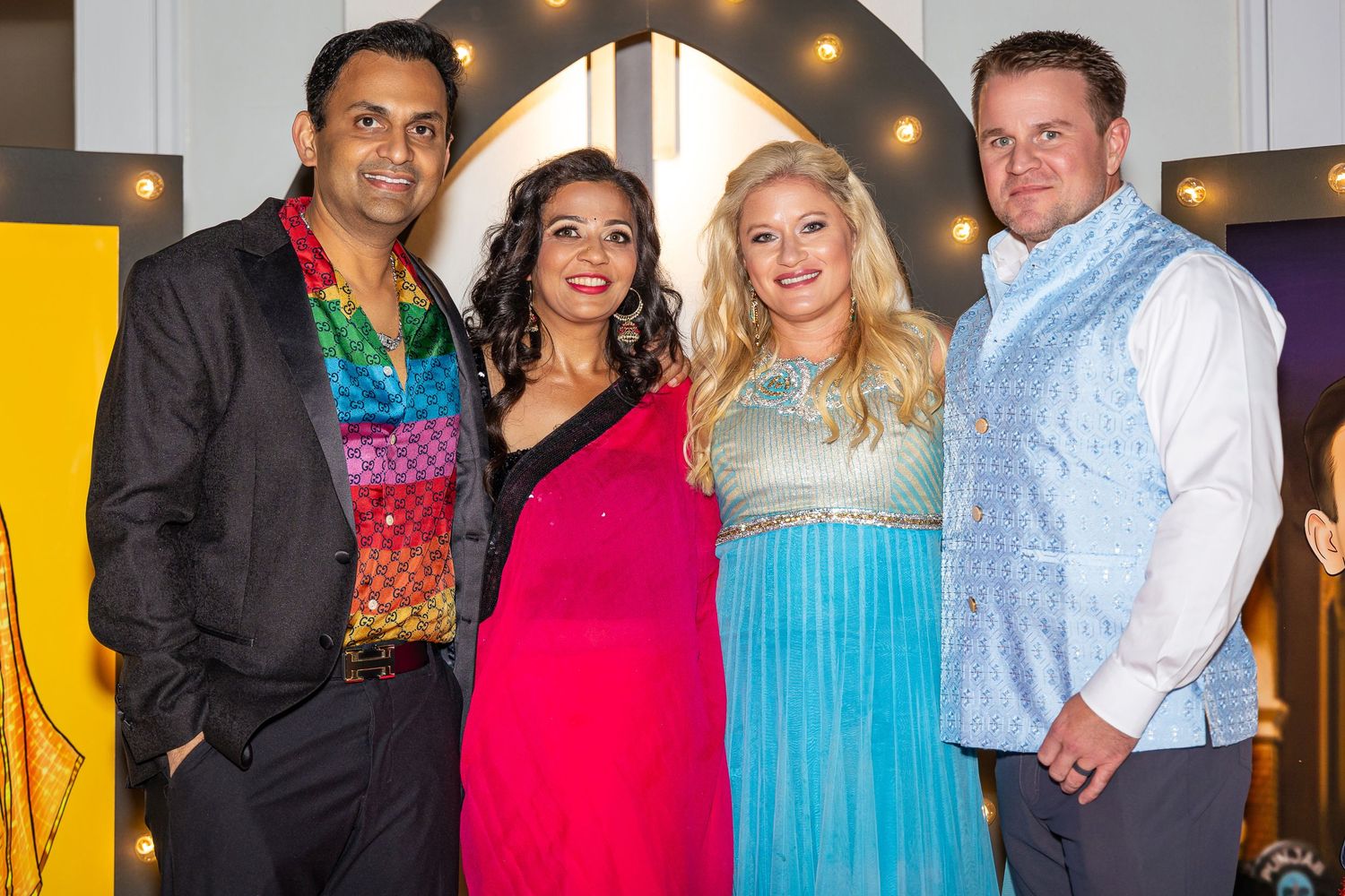 Two couples in colorful formal attire pose together at an event.