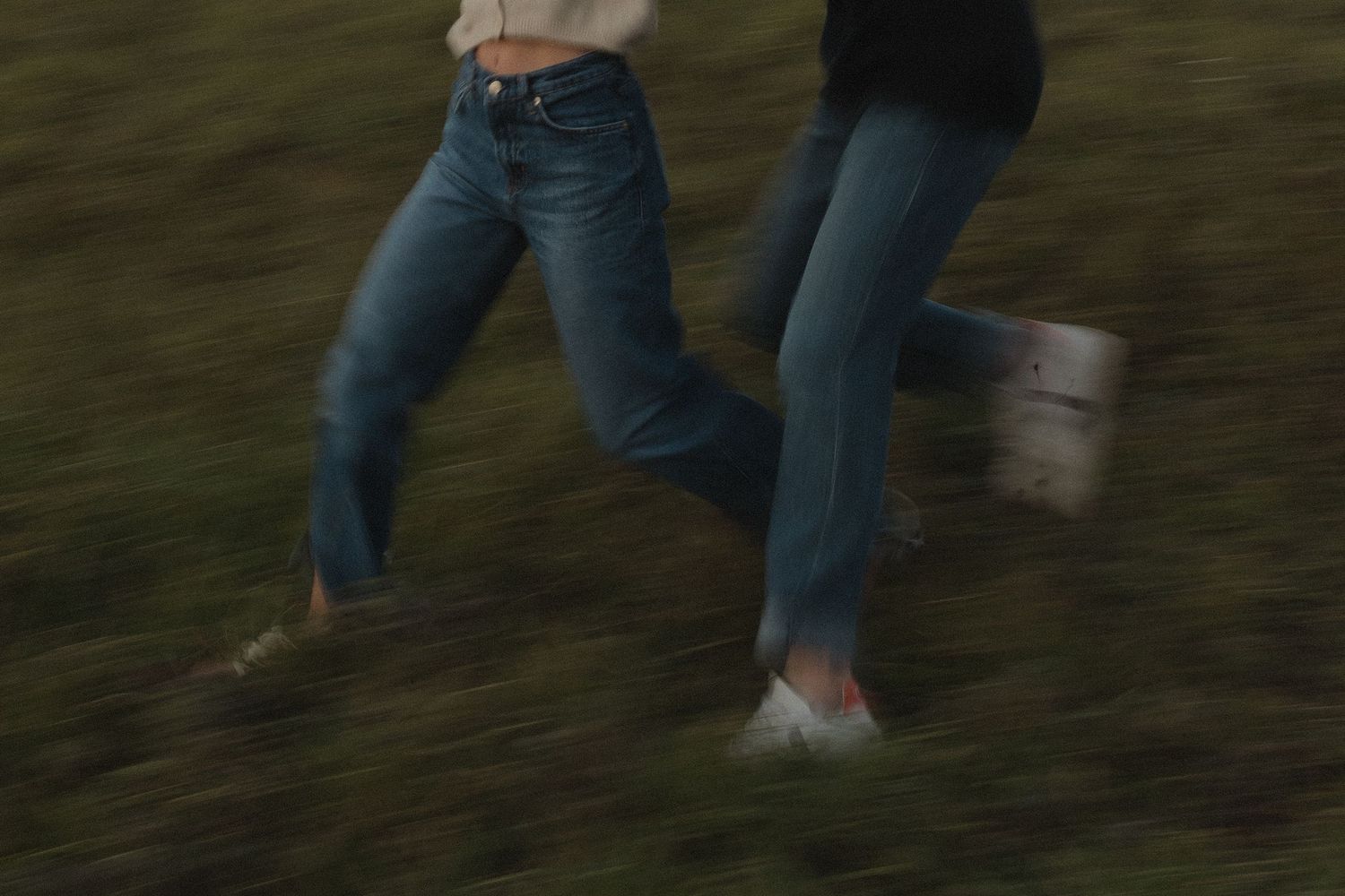 People walking through tall grass at dusk with motion blur effect.