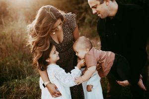 A warm sunset photoshoot in a field captures intimate family moments during golden hour.