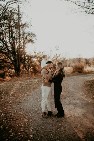 A couple shares a tender moment at sunset on a wooded path during a golden hour photo session.