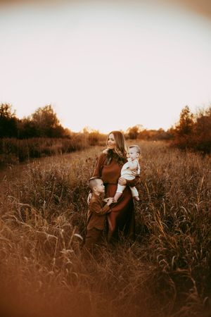 Family plays together in golden sunlit field during sunset portrait session.