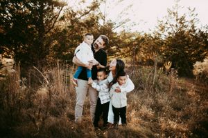 Family enjoys playful outdoor moments together during golden hour photoshoot.