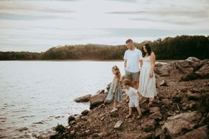 Family portrait session along a rocky lakeshore during sunset.