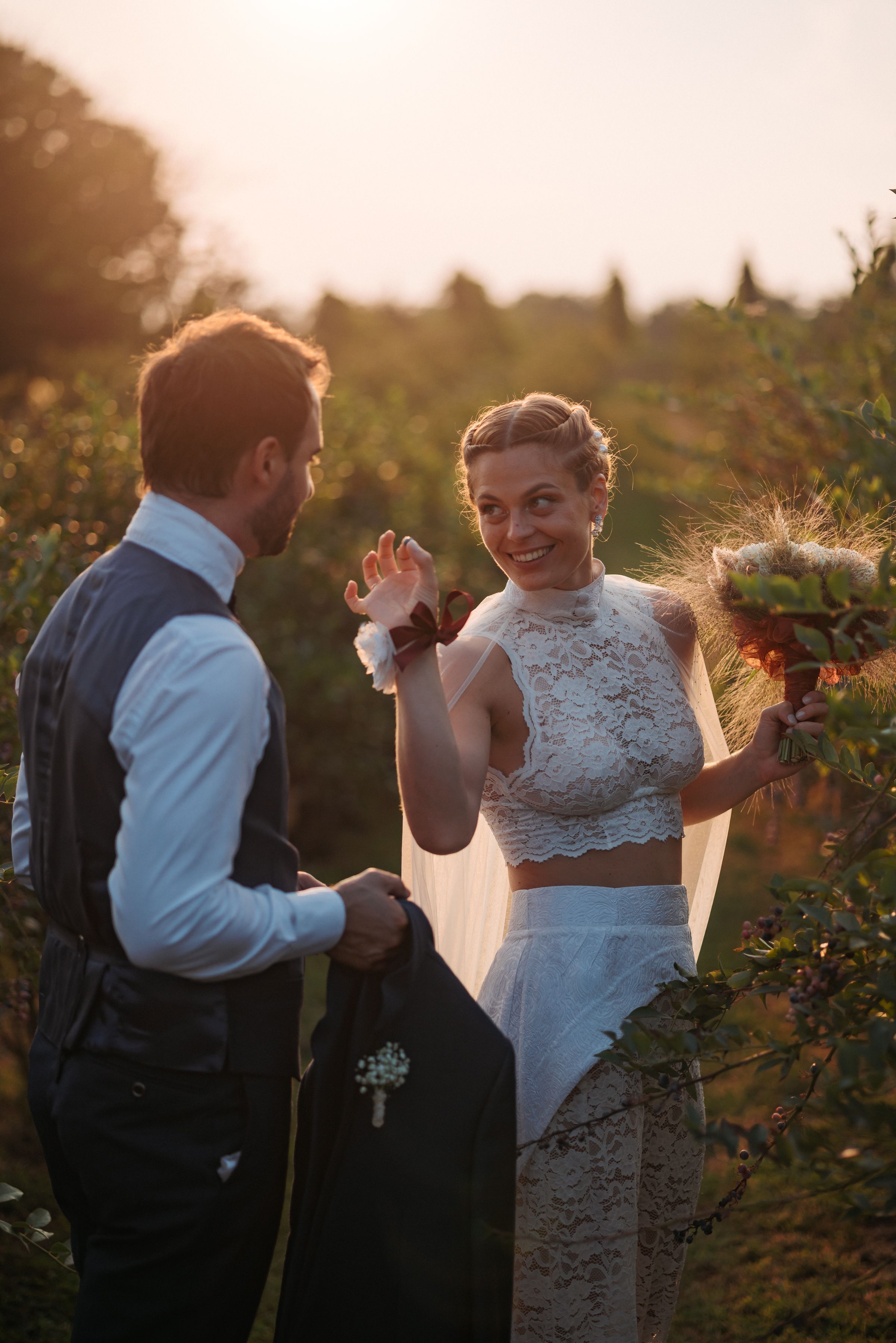 A couple in wedding attire share a romantic moment during sunset in a garden venue.