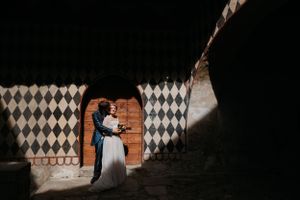 A couple embraces in a doorway with dramatic black and white diamond patterned wall art creating striking contrast.
