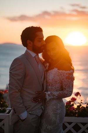 Couple sharing intimate moment at sunset with ocean view and flowers.