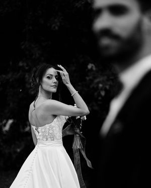 Black and white wedding photo showing bride in strapless lace gown posing elegantly with bouquet.