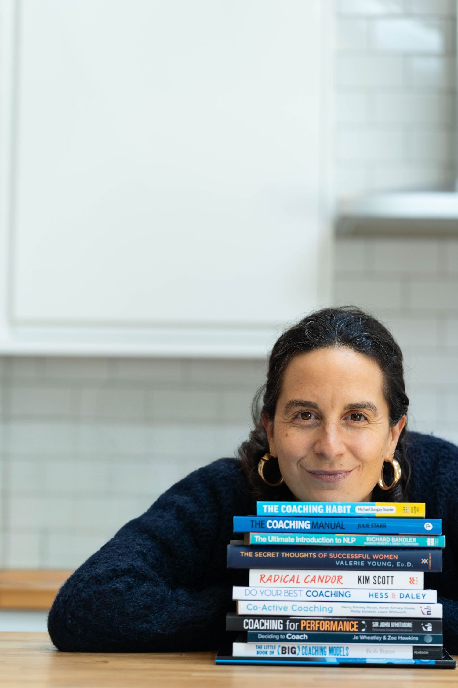 Confidence coach leans on a pile of coaching books in her personal branding photoshoot
