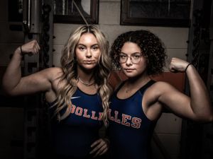 Two athletes in blue uniforms showing strength pose in indoor gym setting. Senior Photos.