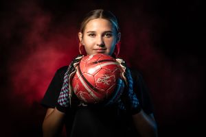 Basketball player holding the ball in dramatic red lighting for intense sports portrait effect.