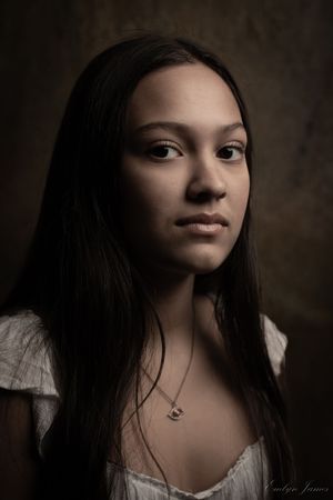 A low key portrait series showing dark hair against shadowy background with dramatic side lighting.