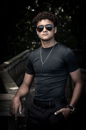 Stylish portrait of person in black t-shirt and sunglasses standing outdoors. Family portrait photography.