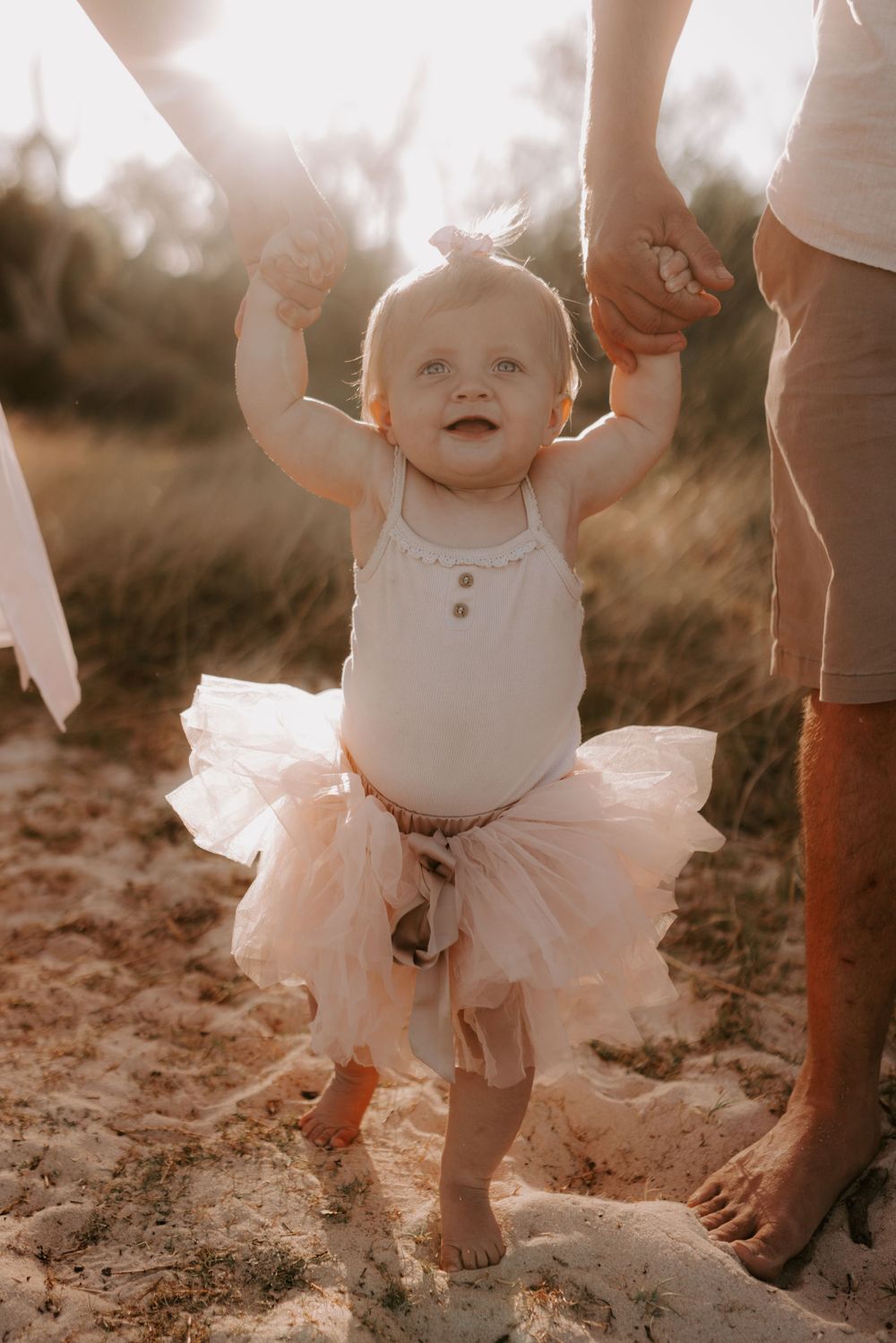 Close-up of small children's feet and legs playing in sand during beach photoshoot.
