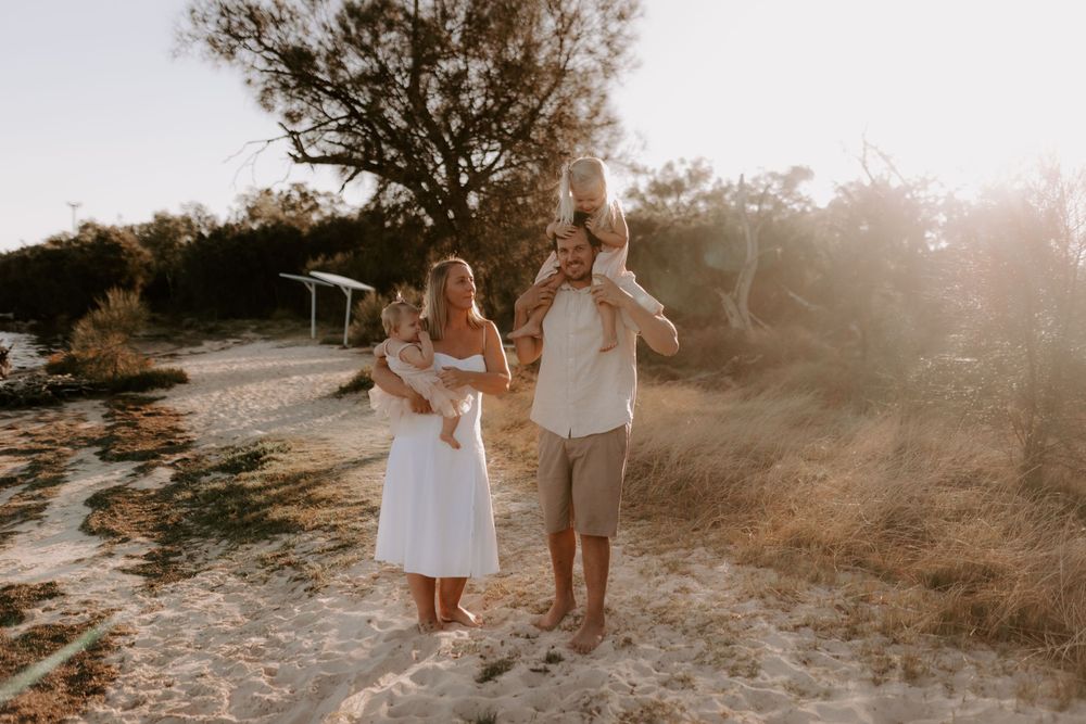 Family walking together on a beach path during golden hour sunset.