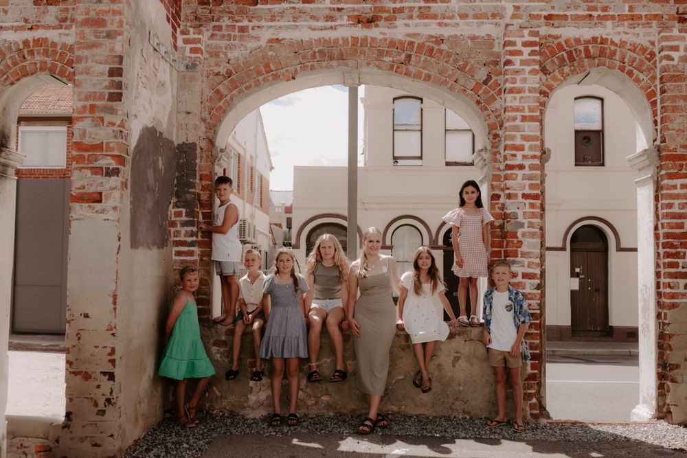 Group portrait inside rustic brick building with arched doorways.