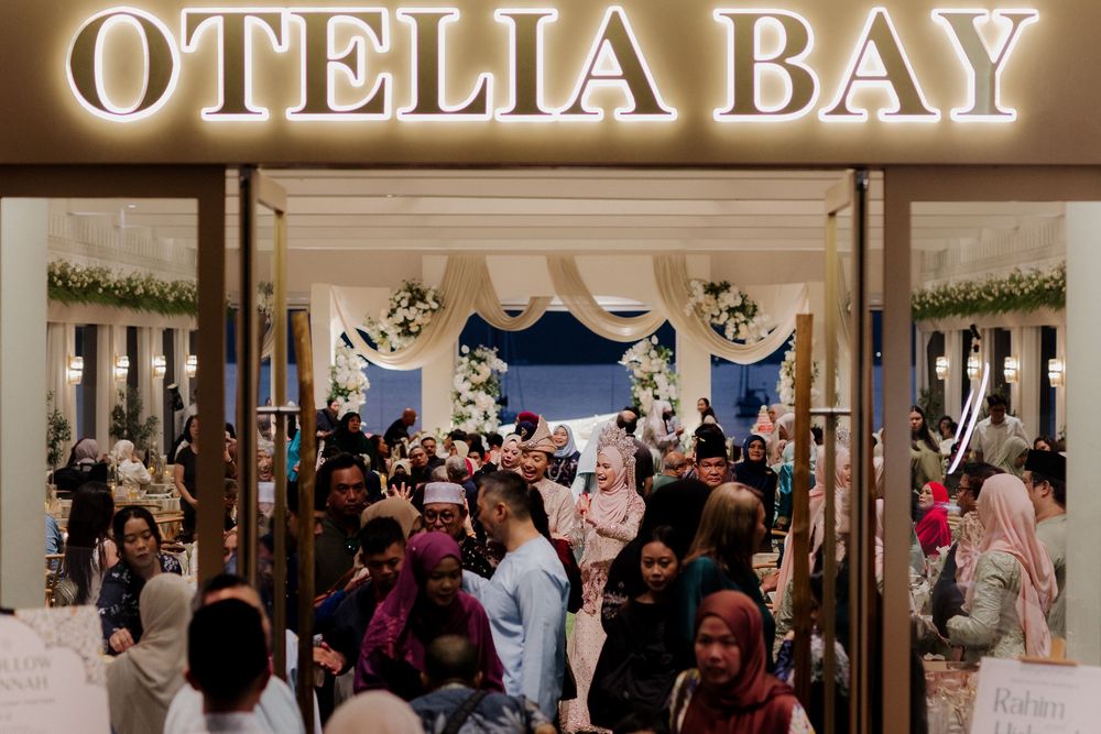 Crowd of shoppers entering Otelia Bay store with elegant white floral wedding decor display inside a mall.