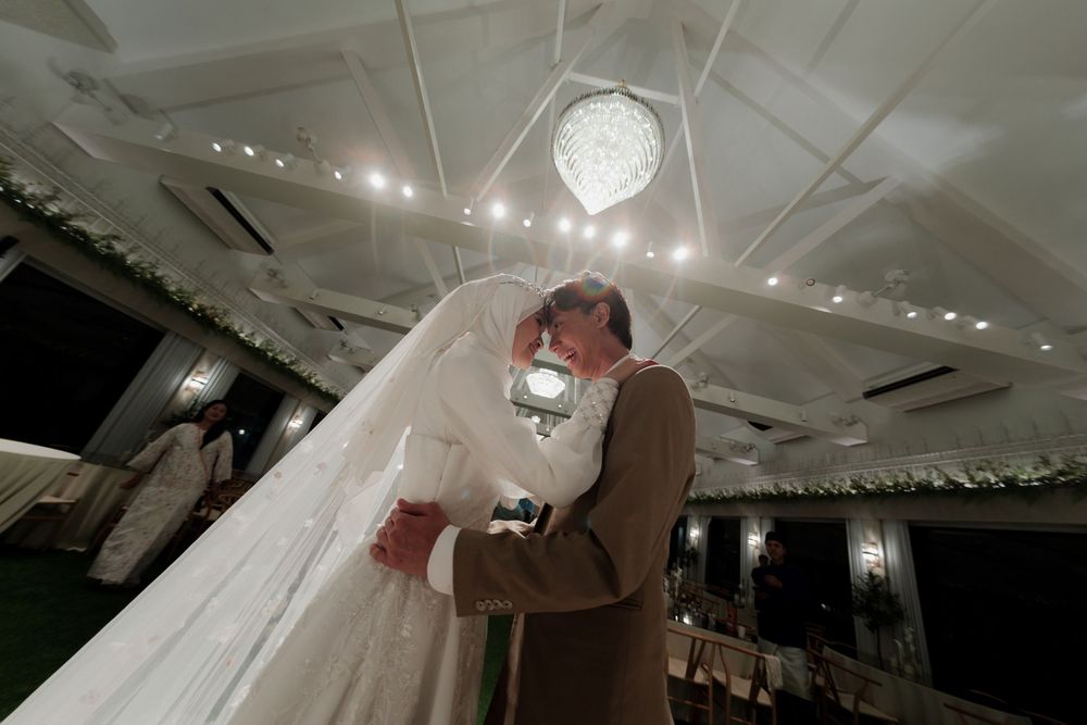 Bride and groom share a romantic first dance under a crystal chandelier in an elegant wedding reception venue.
