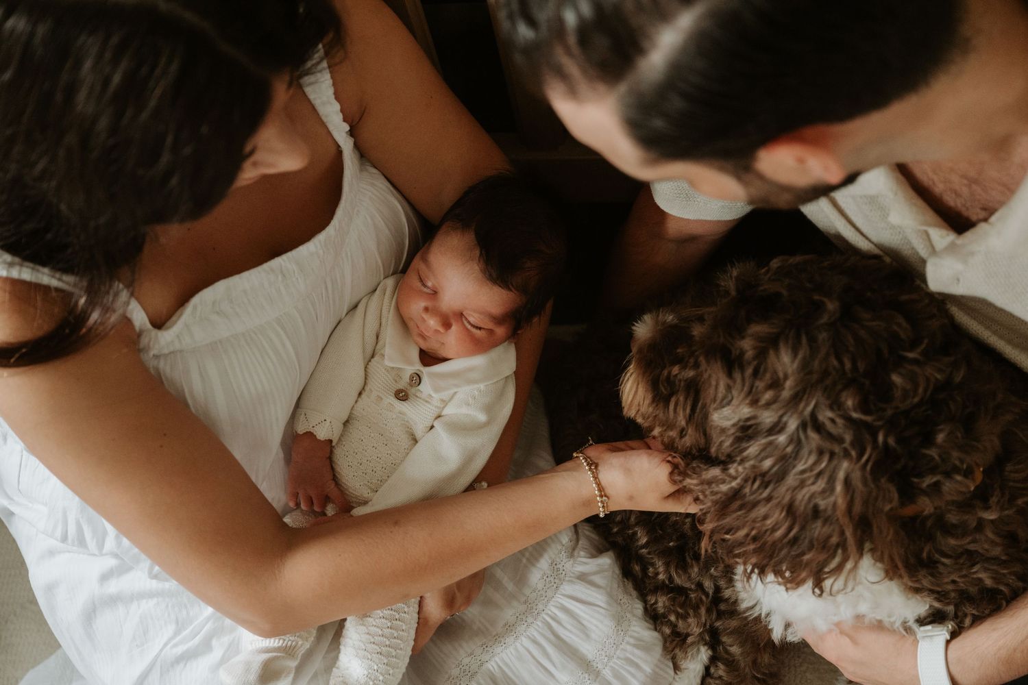 Family cuddling their newborn baby and pet during an in-home lifestyle newborn photography session in New Jersey.