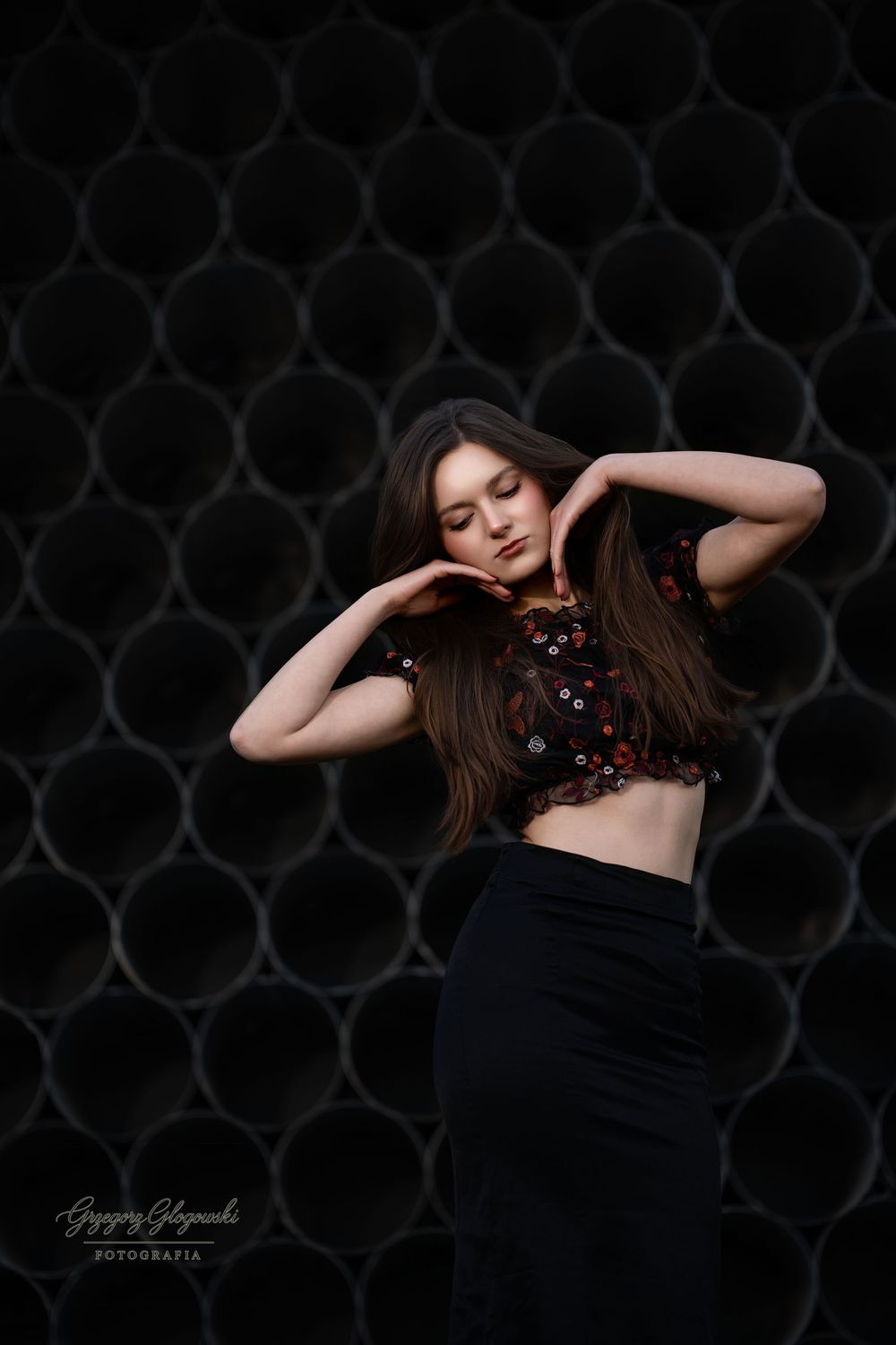 Brunette woman in floral crop top poses gracefully against dark honeycomb background.