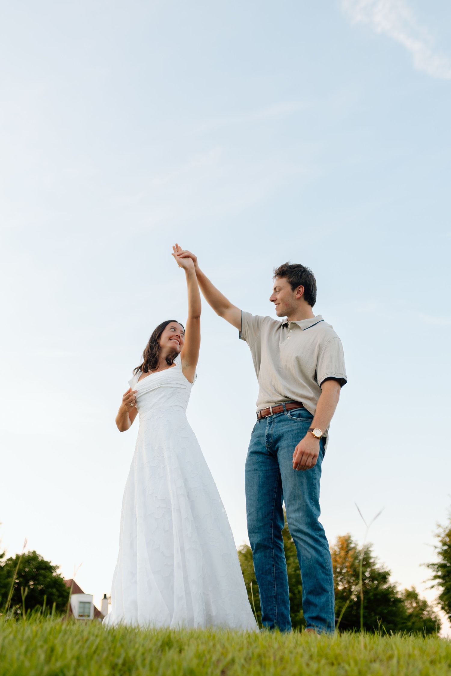 A couple shares a romantic moment in a lush garden, smiling face-to-face in elegant white and light blue attire.