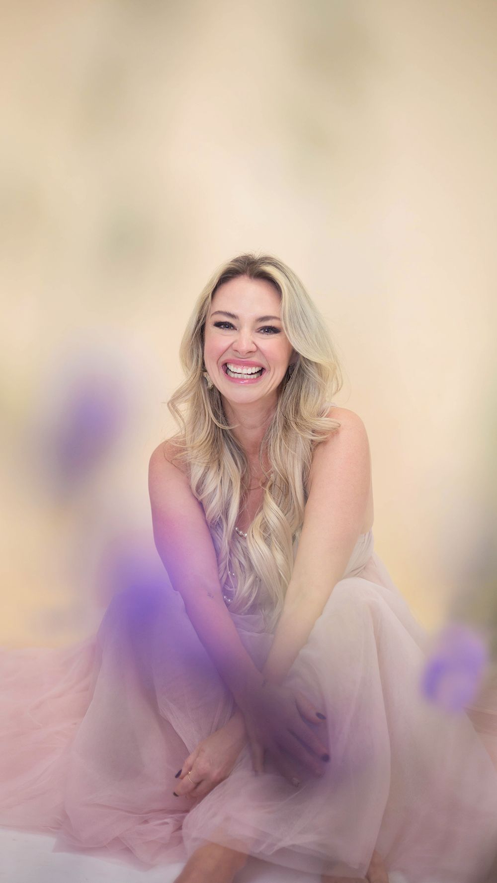 A joyful expression radiates in this dreamy portrait with soft pink tulle and purple accents against a warm background.
