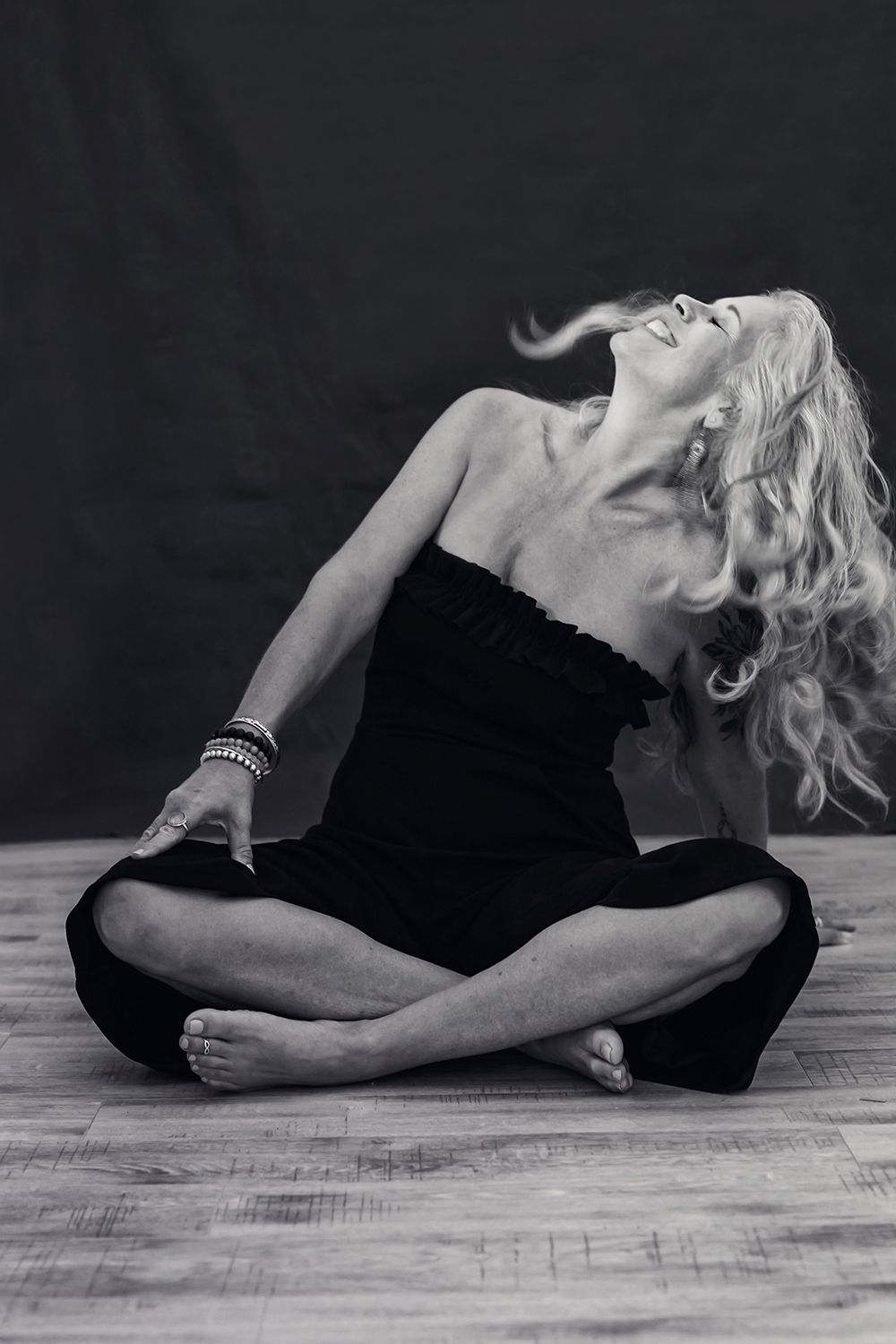 Artistic black and white portrait of person in black outfit sitting in yoga pose.