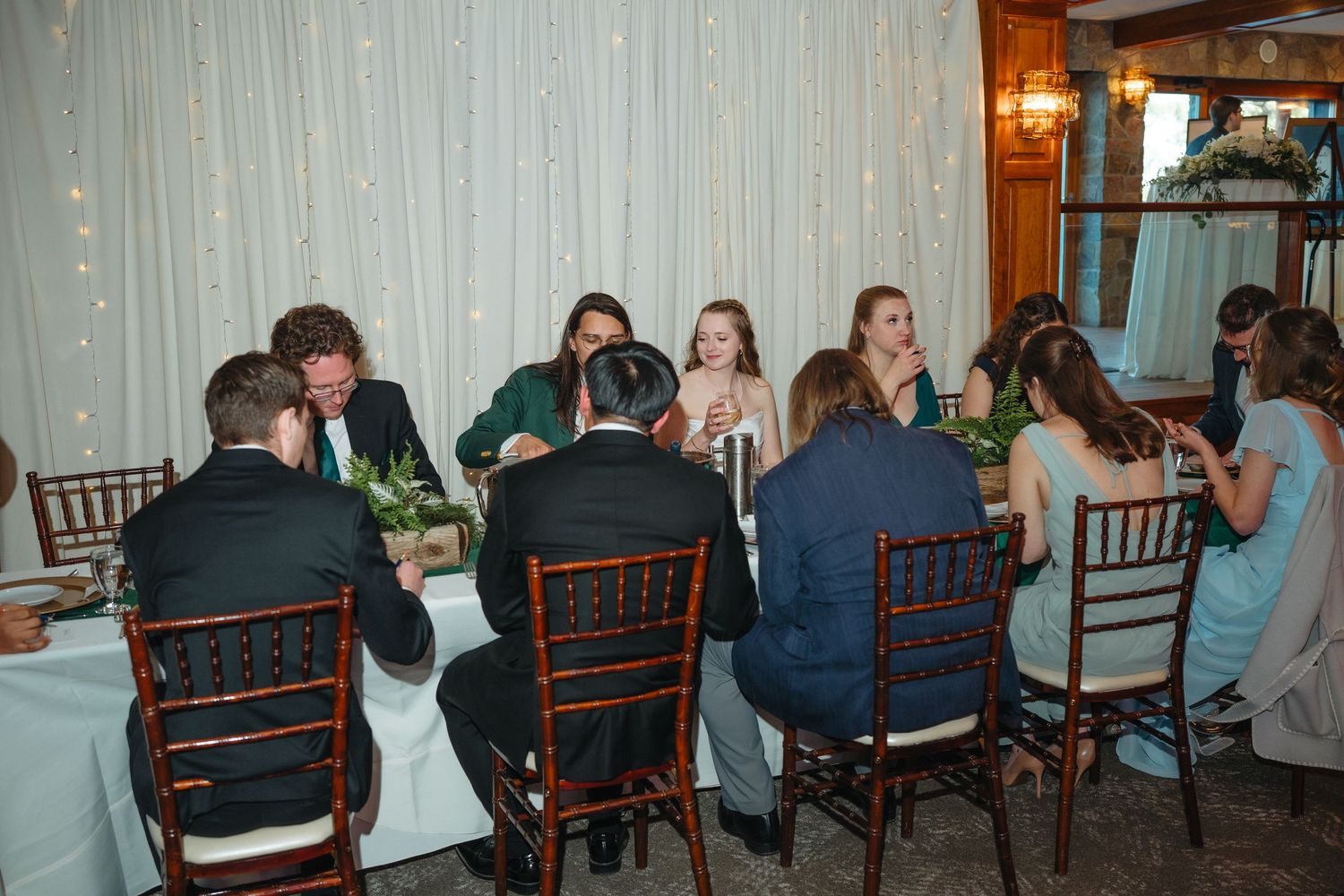 Guests seated at round tables enjoying a wedding reception in an elegant venue with fairy lights.