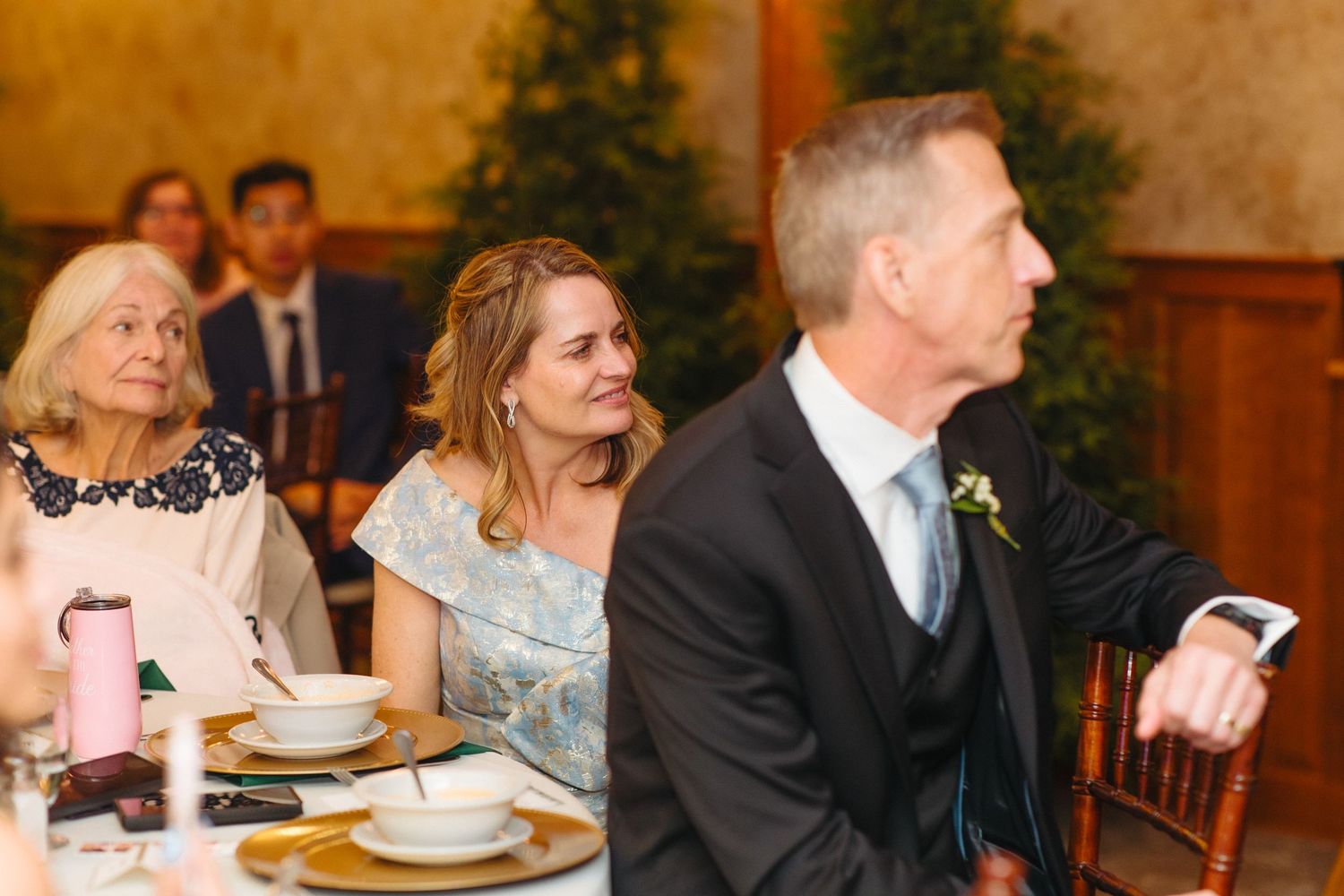 Wedding guests listening attentively to speeches during elegant indoor reception dinner.