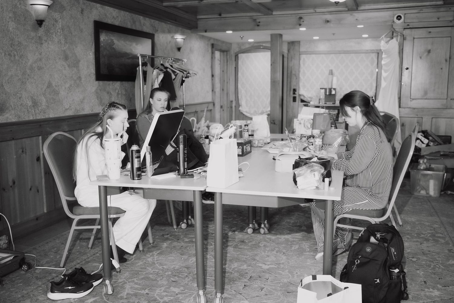 Black and white photo of wedding preparation team working at table in rustic bridal suite.